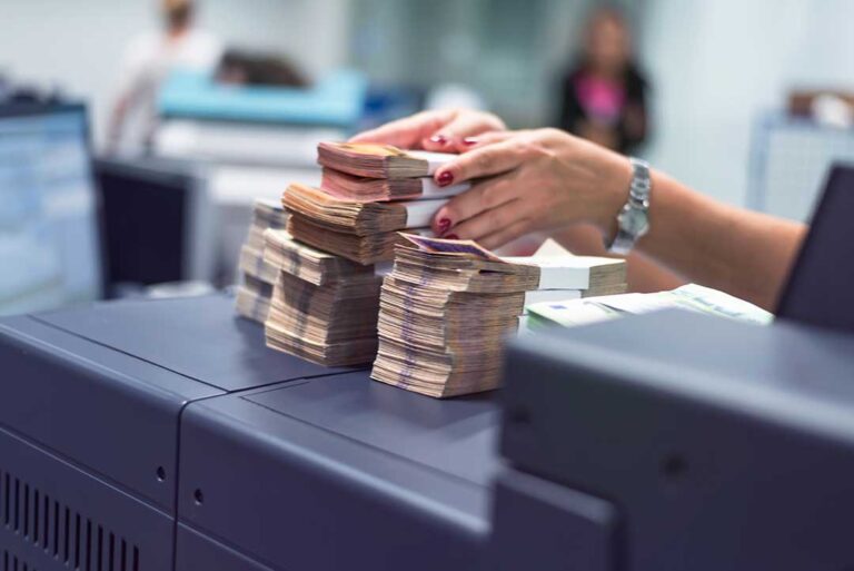 A young adult reviews a credit card statement and checks their credit score on a laptop at home.
